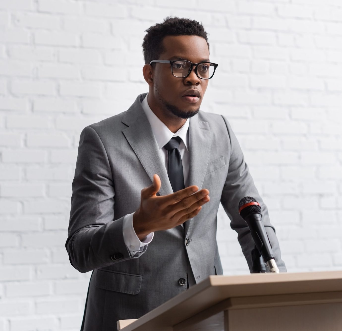 confident-african-american-business-speaker-on-tribune-with-microphone-in-conference-hall-e1661098107411.jpg